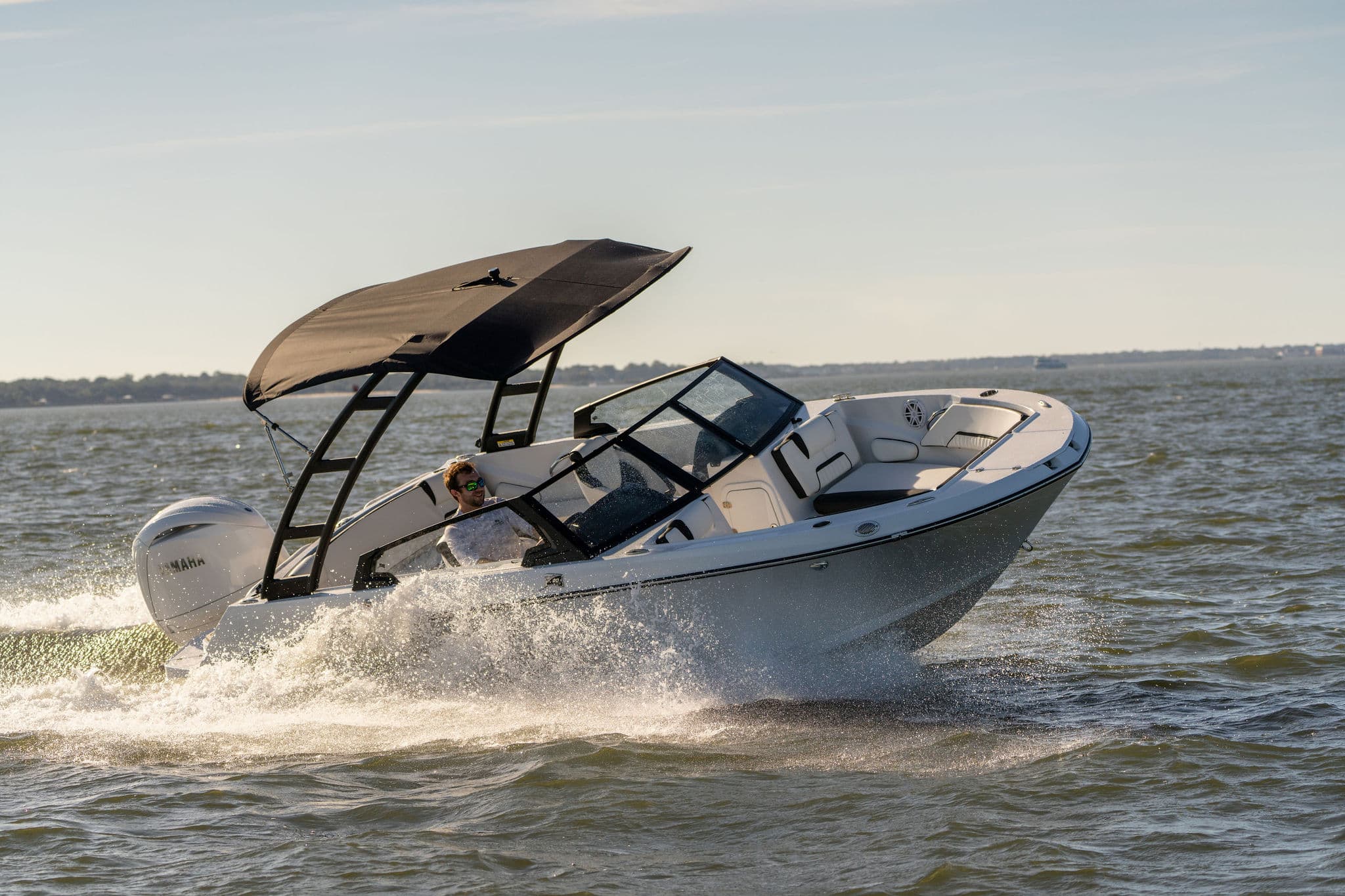 Stingray boat speeding on water with wake and wakeboard tower.