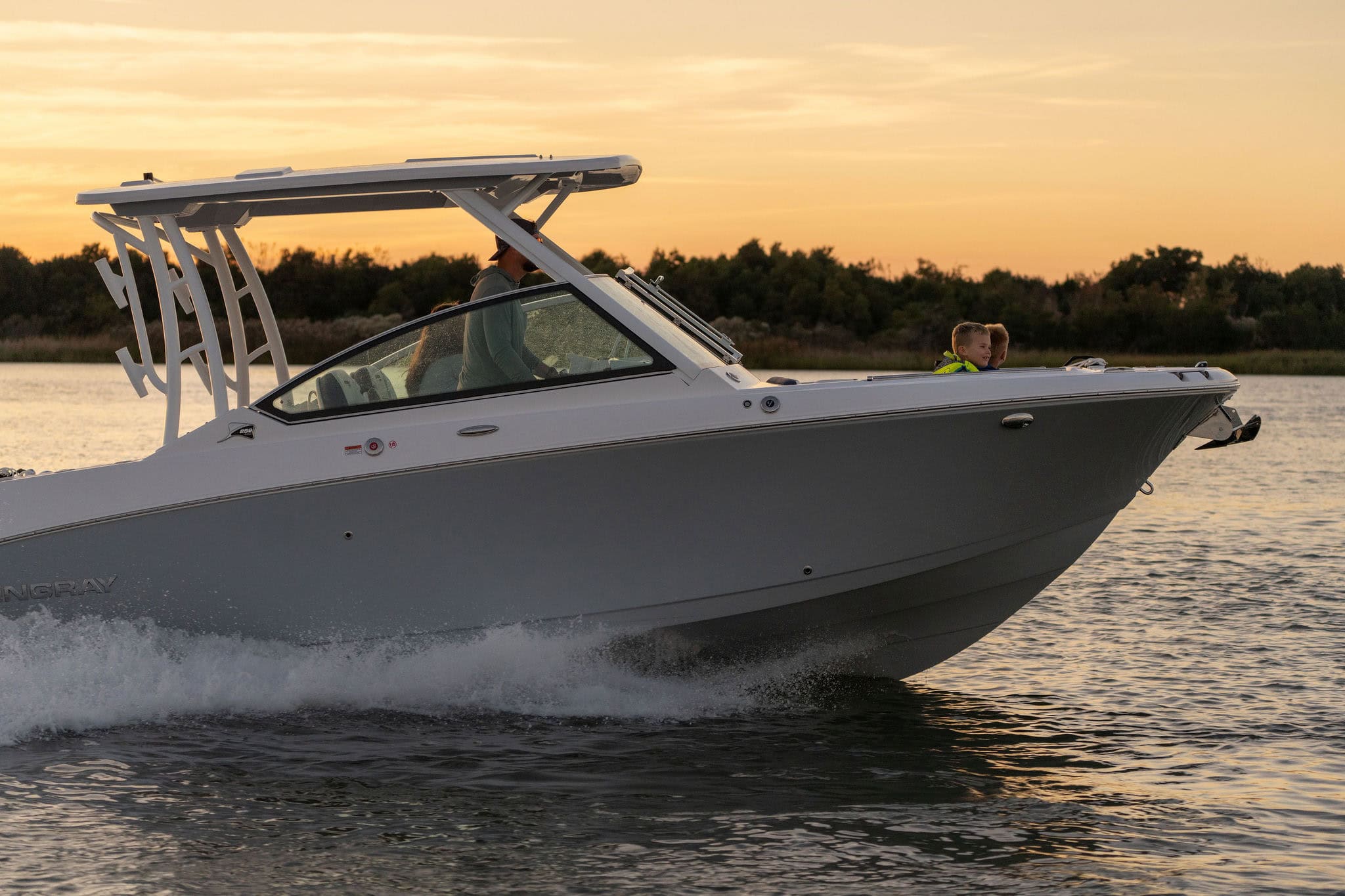 Modern Stingray boat cruising on water at sunset with a clear sky.